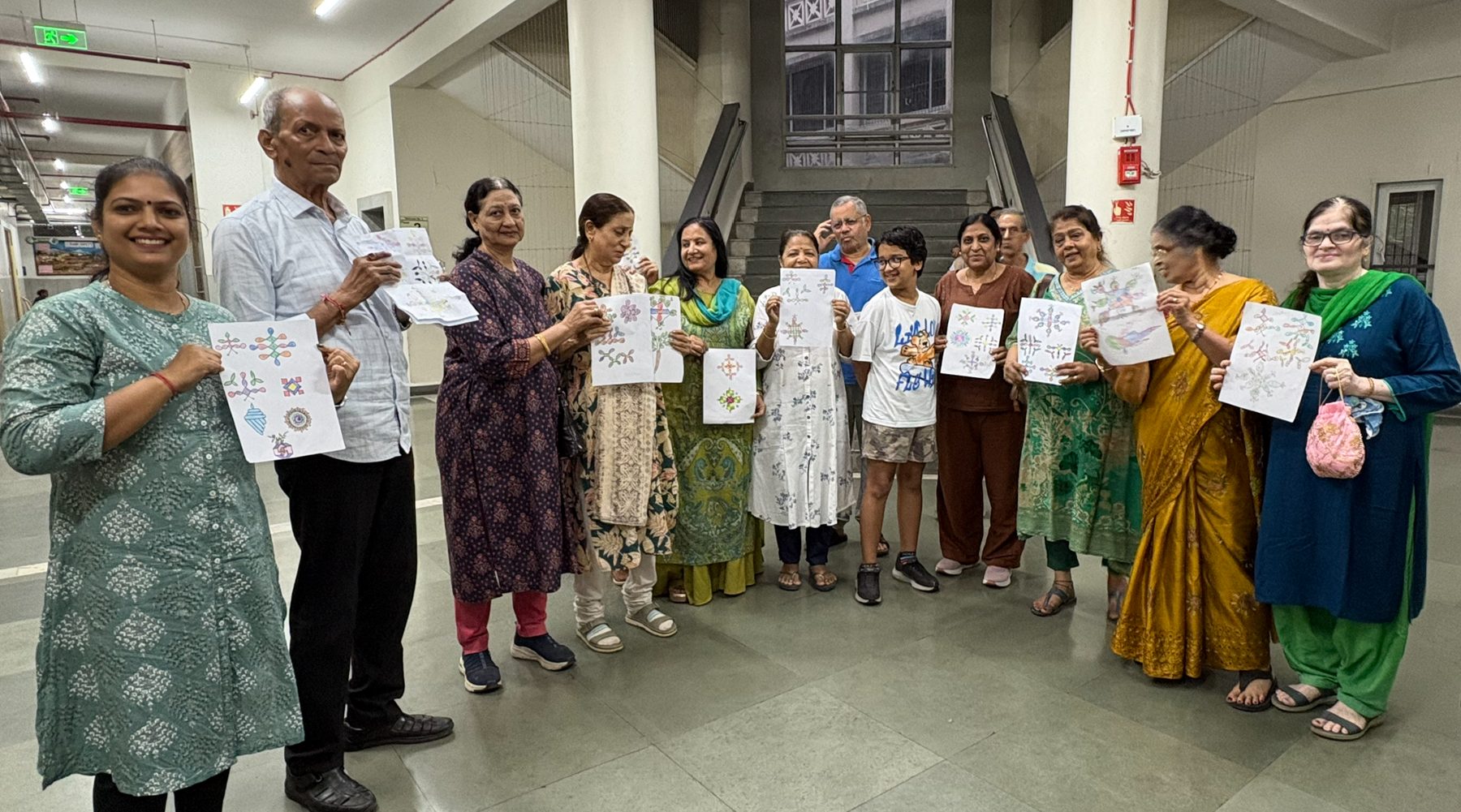 A group of workshop participants standing together holding up the artwork they created during a NeuroKala session.