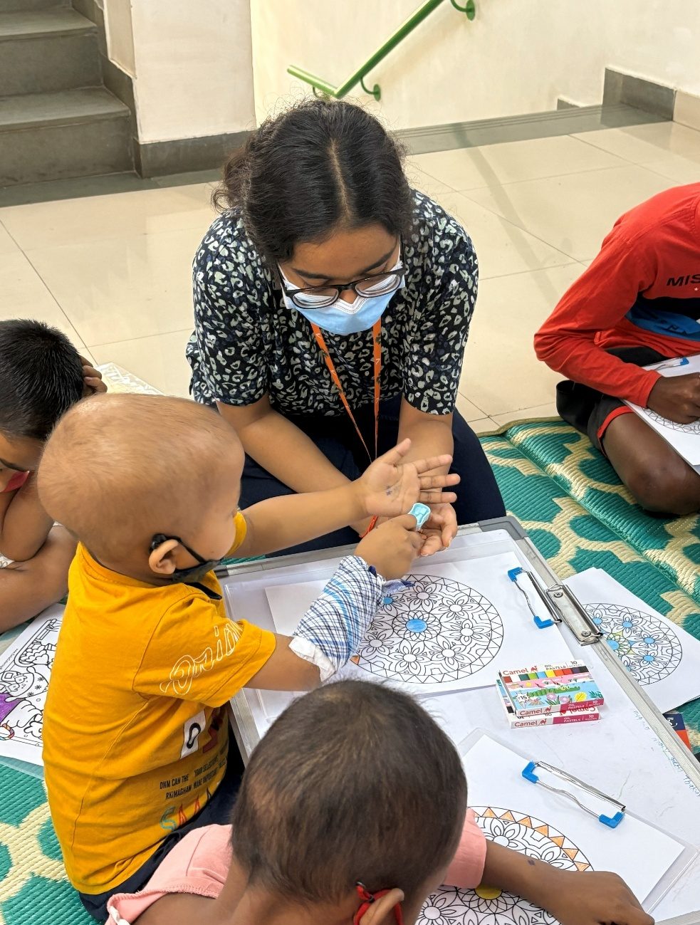 A volunteer helping young children draw mandalas during a session.