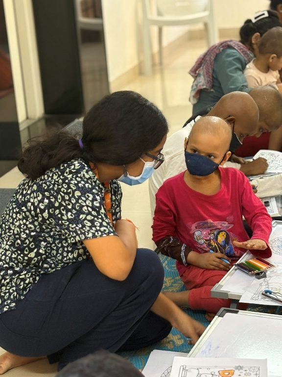 A volunteer sitting with children during an art session.