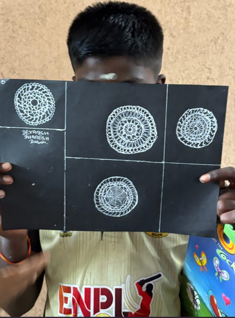 A child holding up a sheet of four completed mandala drawings.