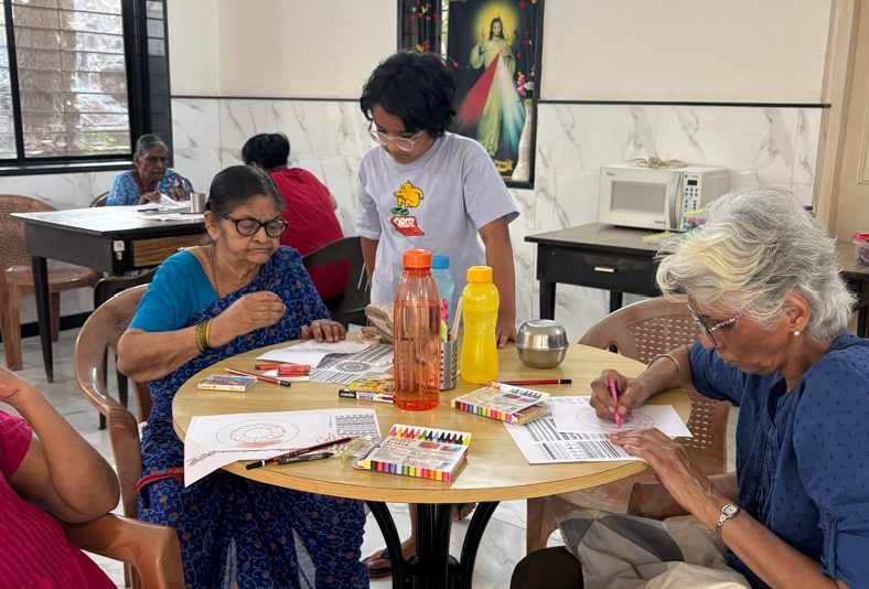 A small group of participants at a table with art supplies spread between them.